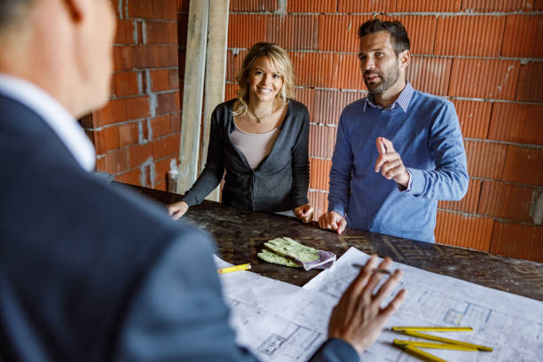 istock Young couple talking to real estate agent at construction site. 1226385764