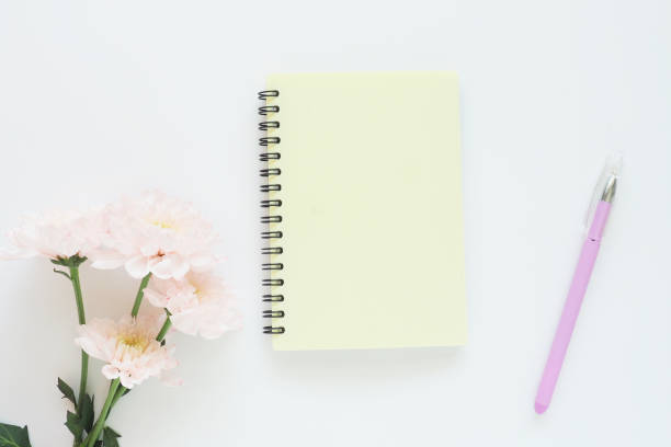 istock mock up yellow notebook on a spring, gently pink chrysanthemums and a lilac pen on a white background. Space for text. 1226386317