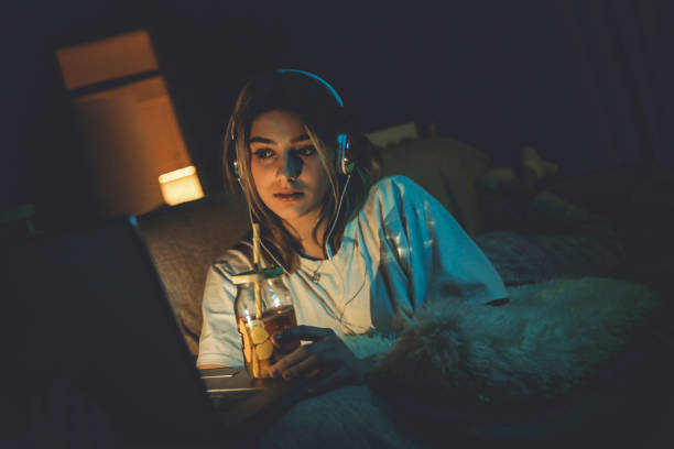 Teenager girl watching online movie Single woman watching online movie in the night sitting on a couch in the living room at home free girl download stock pictures, royalty-free photos & images