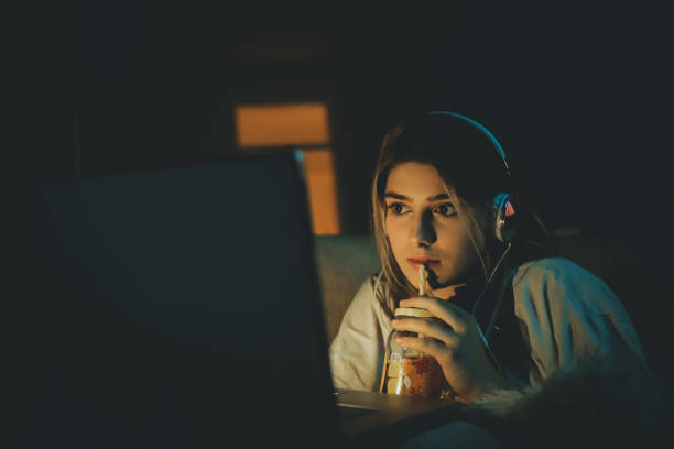 Teenager girl watching online movie Single woman watching online movie in the night sitting on a couch in the living room at home free girl download stock pictures, royalty-free photos & images