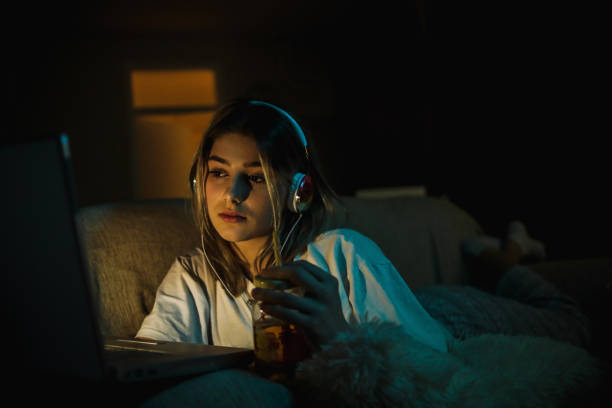 Teenager girl watching online movie Single woman watching online movie in the night sitting on a couch in the living room at home free girl download stock pictures, royalty-free photos & images