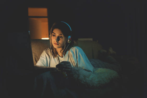 Teenager girl watching online movie Single woman watching online movie in the night sitting on a couch in the living room at home free girl download stock pictures, royalty-free photos & images