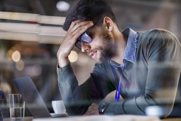 businessman with hypnosis eyeglasses having a headache in the office. - looking through window businessman problems reading imagens e fotografias de stock