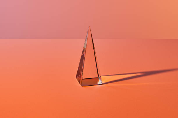 istock crystal transparent pyramid with light reflection on orange background 1226391452