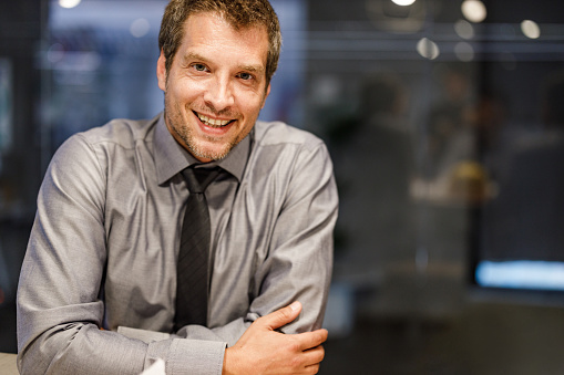 Happy male entrepreneur relaxing in the office and looking at camera. Copy space.