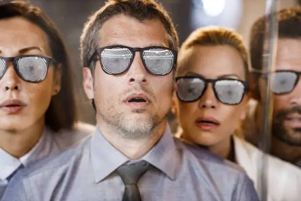 Group of controlled people with hypnotic eyeglasses who are unable to see the real picture.