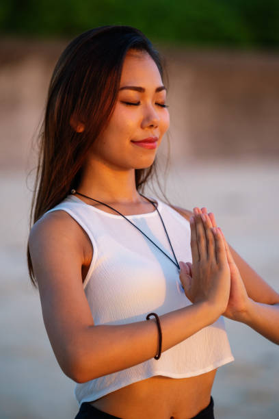 istock Young woman practicing yoga on the beach in the evening 1226395765