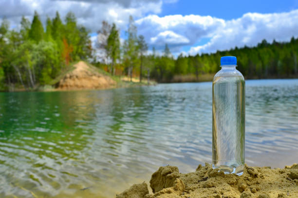 istock A closed plastic water bottle with a close up stands on a sandy beach against the background of clear lake water. 1226396076