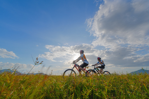 family couple lover enjoy the life of riding biking on the fresh field meadow grass, cheerfully life holding hand together on outdoors activity
