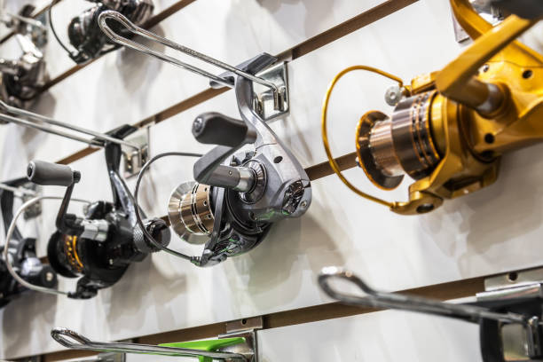 fishing reels of different sizes on the counter in the fishing store - carretel de pesca imagens e fotografias de stock
