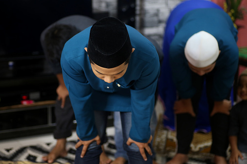 Portrait of Muslim prayers 'Rukuk' (the act of belt-low bowing where hands are rested on the knees) at home in Malaysia.