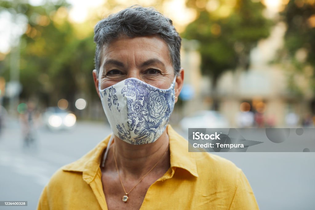One midle aged woman wearing a protective mask and smiling One person wearing a protective mask and smiling Protective Face Mask Stock Photo