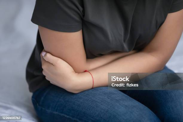 Closeup Image Woman Sitting In Bed Feeling Stomach Ache Stock Photo - Download Image Now