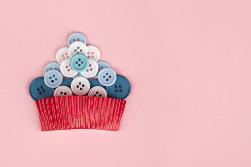 Cupcake made of  sewing buttons isolated on pink background