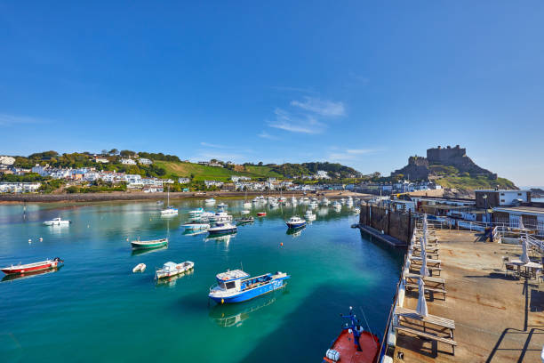 Gorey Harbour Image of Gorey Harbour with fishing and pleasure boats, the pier bullworks and Gorey Castle in the background with blue sky. Jersey, Channel Islands, UK channel islands england stock pictures, royalty-free photos & images