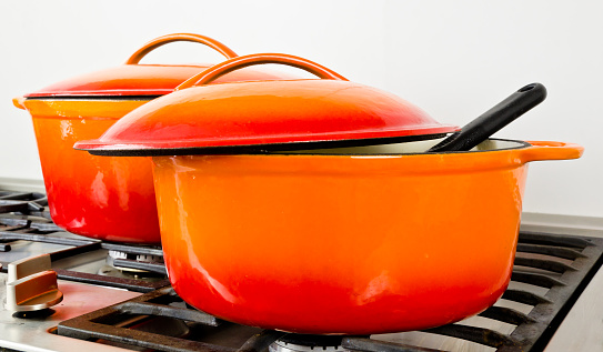 dos ollas de color naranja brillante de hierro fundido con esmalte en una vieja estufa de gas vintage photo