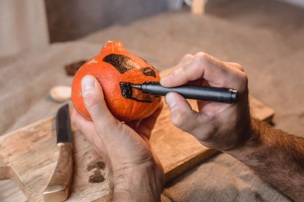 istock Man cuts out pumpkin for halloween 1226409279