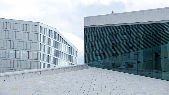 Oslo, Norway - May 22, 2019: The glass façade of the Oslo Opera House and surrounding modern architecture buildings in the downtown district of the capital city of Norway.