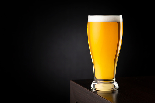 Cold pale beer in a beer glass placed on a bar counter with copy space