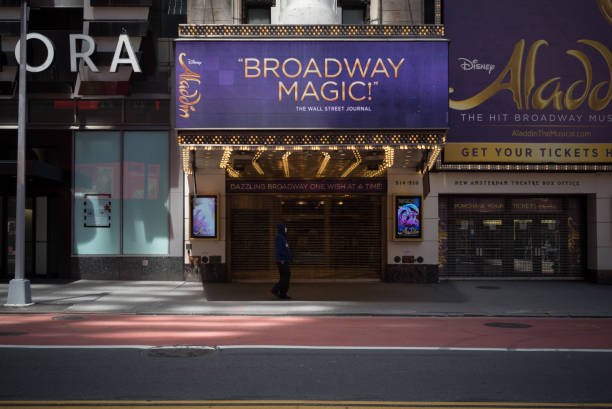 New York during the COVID-19 emergency. May 20, 2020. Manhattan, New York, Usa. A man wearing a mask walks in front of the empty entrance of the New Amsterdam Theatre on 42nd street featuring the Broadway show "Aladdin". The show has been suspended due to the lockdown measure to avoid further spread of the coronavirus. Broadway performances were cancelled on March 12, 2020 when 31 productions were running, including 8 new shows in previews. 42nd street photos stock pictures, royalty-free photos & images