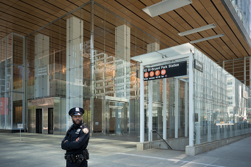 May 20, 2020. Manhattan, New York, Usa. A policeman patrols the streets at 1 Bryant Park in front of the entrance of an empty subway station at the Bank of America Tower. The coronavirus outbreak in New York City has taken a major toll on workers in health care, mass transit, and public safety, including the New York City Police Department.