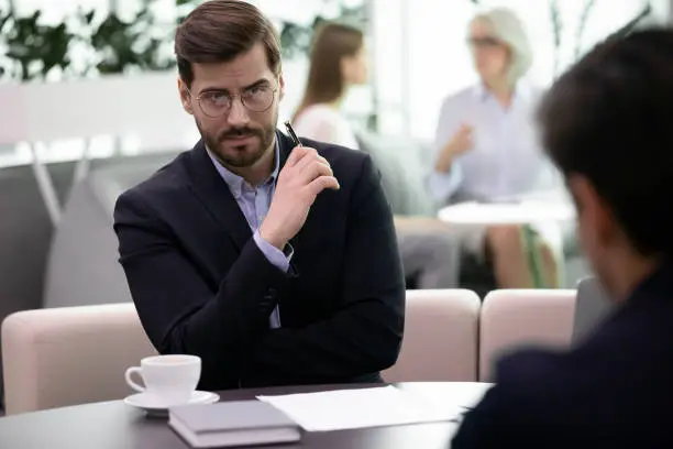 Two business men partners during meeting in office. Negative attitude to applicant, bad first impression, hr manager looking at candidature with distrust, unsuccessful, failed job interview concept