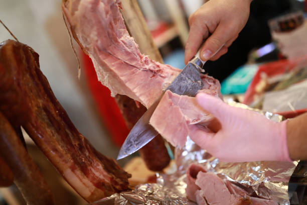 istock Person cuts slice of pork ham 1226413252