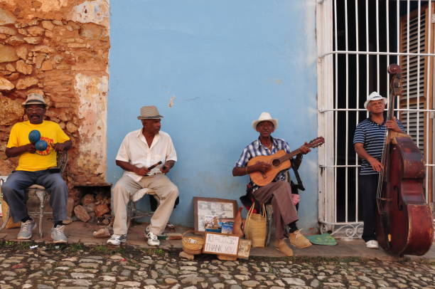 Trinidad, Cuba - March 22, 2017: Group of cuban men are playing traditional music on the streets of Trinidad whilst different people are dancing in the rythm of the music