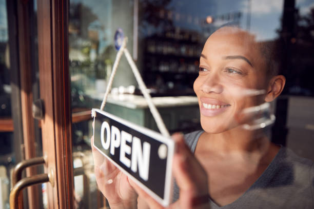 propriétaire féminin du café de démarrage ou d’un restaurant tournant autour du signe ouvert sur la porte - american business photos et images de collection