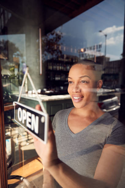 dona de startup de café ou restaurante virando placa aberta na porta - owner small business restaurant african ethnicity - fotografias e filmes do acervo