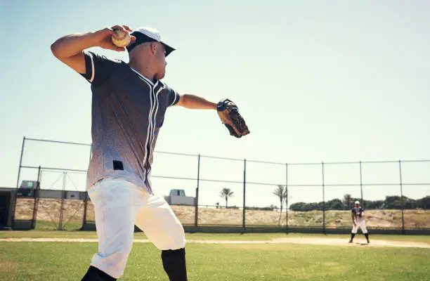 Shot of a young man pitching a ball during a baseball match