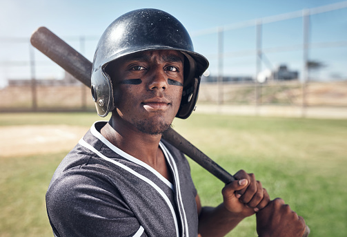 Shot of a young man swinging his bat at a baseball game