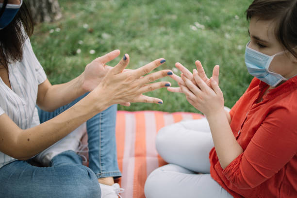 istock Cropped girls rubbing their hands with disinfectant while sitting on mat in forest 1226420767