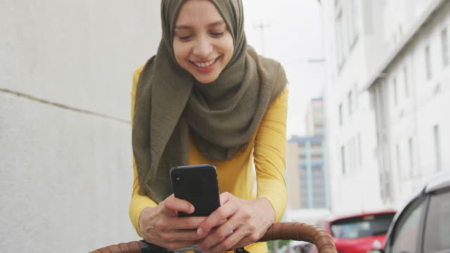 Woman wearing hijab using her phone on a bike