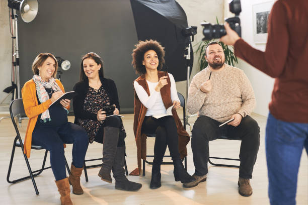 istock Young handsome bearded educator showing to his multicultural attendees how camera works. Photo studio interior. 1226420996