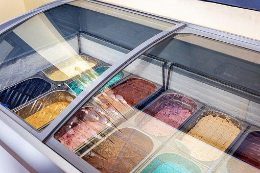 Ice cream serving counter with many scoopable flavors.Assorted Flavors of Icecream in the counter