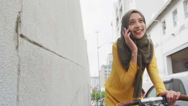 Woman wearing hijab having a phonecall on a bike