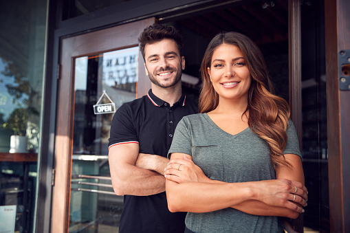 Retrato de pareja comenzando nueva cafetería o negocio de restaurantes de pie en doorway photo