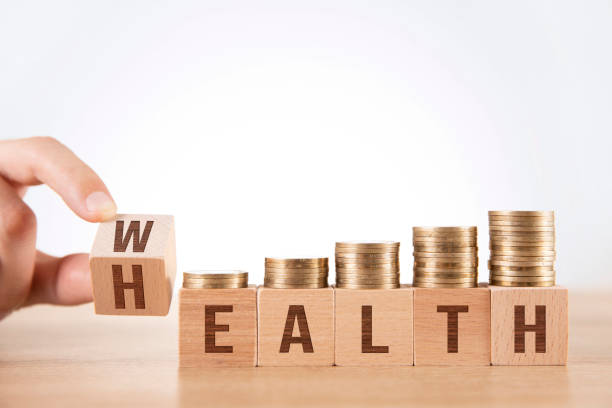 istock Hand Flip Wooden Cube with Word Wealth to Health with Coins Stack 1226422130