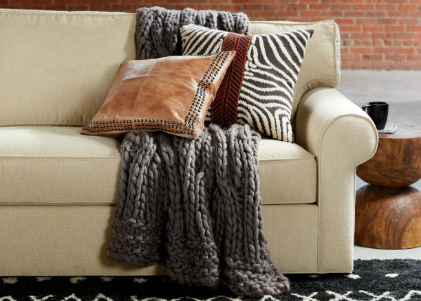Cozy interiors, living room Sofa with pillows and knitted blanket, close up. Cozy interiors, living room Sofa with pillows and knitted blanket, close up. Knitted plaid and pillows on a sofa at home. Home cosiness. plaid couch stock pictures, royalty-free photos & images