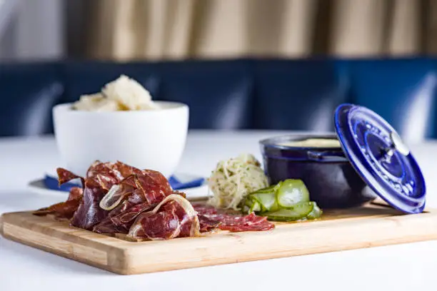 Cold cuts with pickles and onion on a wooden board, side view, blurry background. Various Sliced Cold Cuts with Pickles and olives.