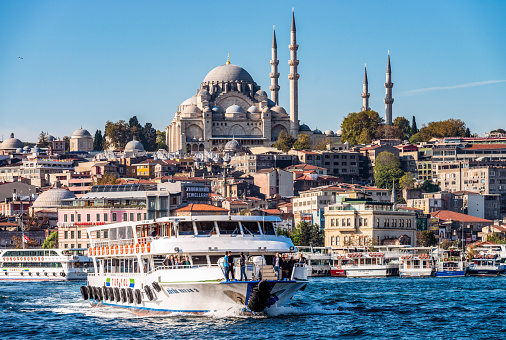 Istanbul, Turkey - Passengers on a Turyol tour ferry, in the Golden Horn in central Istanbul, with Suleymaniye Mosque on the horizon.