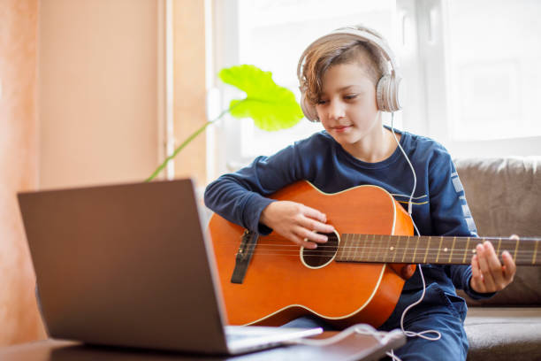istock Kid with headphones learning how to play guitar with his laptop on 1226423607