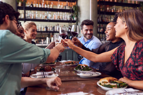 grupo de amigos se reúnen en el restaurante celebrando y haciendo un brindis - afterwork business fotografías e imágenes de stock