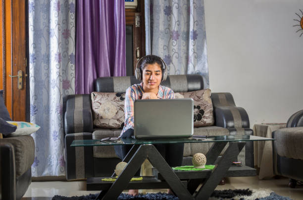 fille indienne occupée dans un appel vidéo utilisant l’ordinateur portatif et le casque à la maison - indian girls audio photos et images de collection