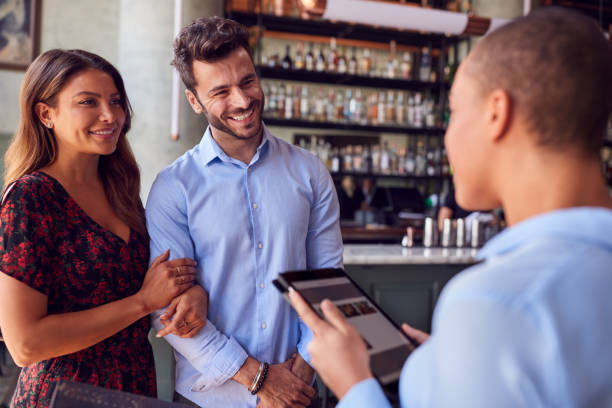 istock Couple Being Greeted By Maitre D Using Digital Tablet As They Arrive At Restaurant 1226424877