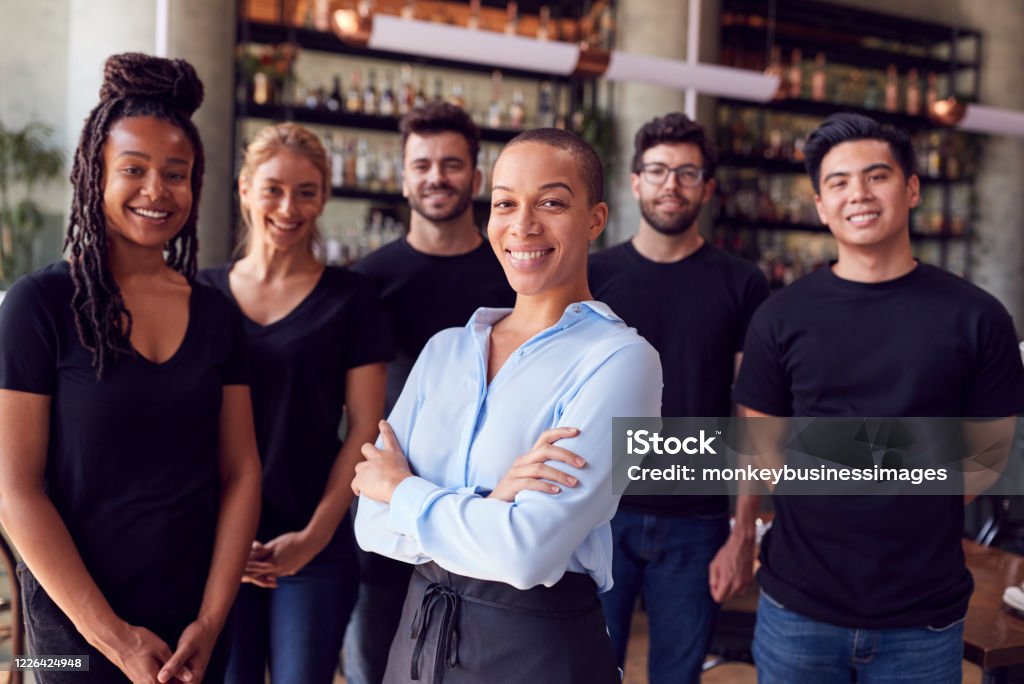 Portrait Of Female Owner Of Restaurant Bar With Team Of Waiting Staff Standing By Counter Restaurant Stock Photo