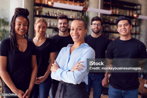 Portrait Of Female Owner Of Restaurant Bar With Team Of Waiting Staff Standing By Counter Stock Photo - Download Image Now