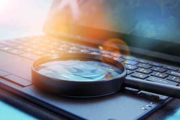 Laptop computer with magnifying glass stock photo