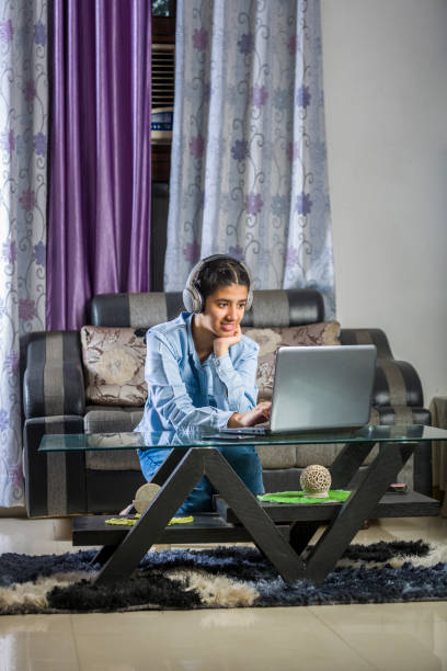 une fille indienne fait l’étude en ligne utilisant l’ordinateur portatif et le casque à la maison - indian girls audio photos et images de collection